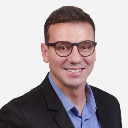 Túlio Baita: homem jovem, pele branca, cabelo curto e liso.